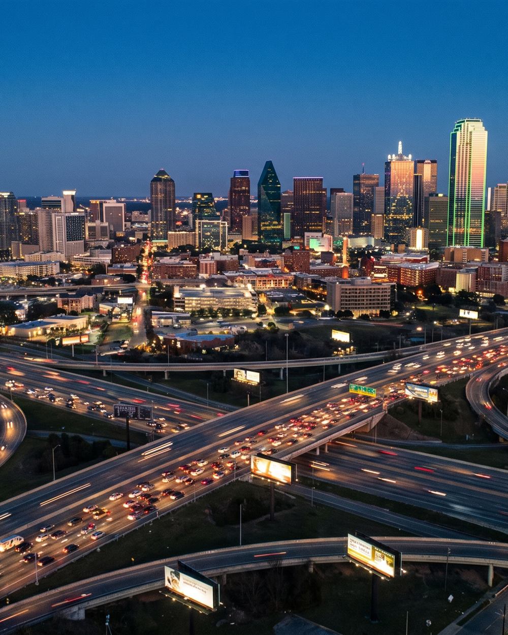 Aerial view of a highway network with illuminated billboards at dusk