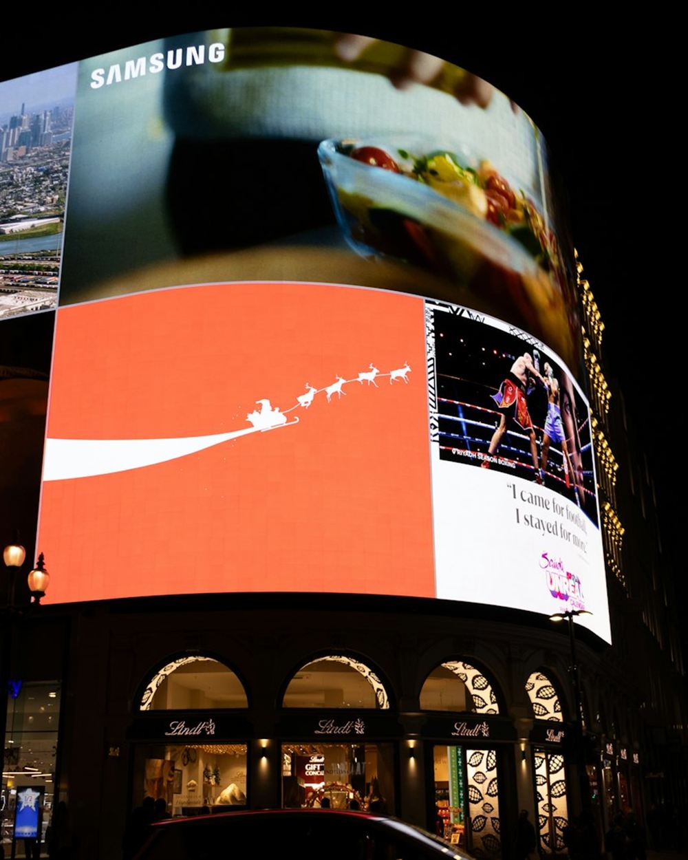Curved digital LED billboard display in a busy city district