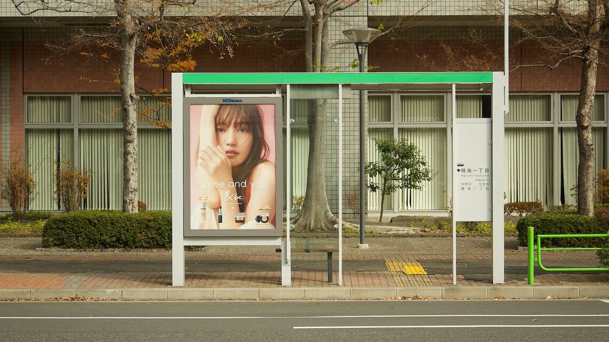 Street-level advertising poster panel at a city bus shelter